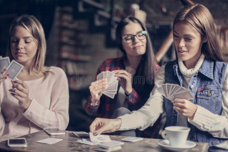 Tre flickor som spelar kortet i kafé royaltyfri fotografi Tre flickor som spelar kortet i kafé royaltyfri fotografi