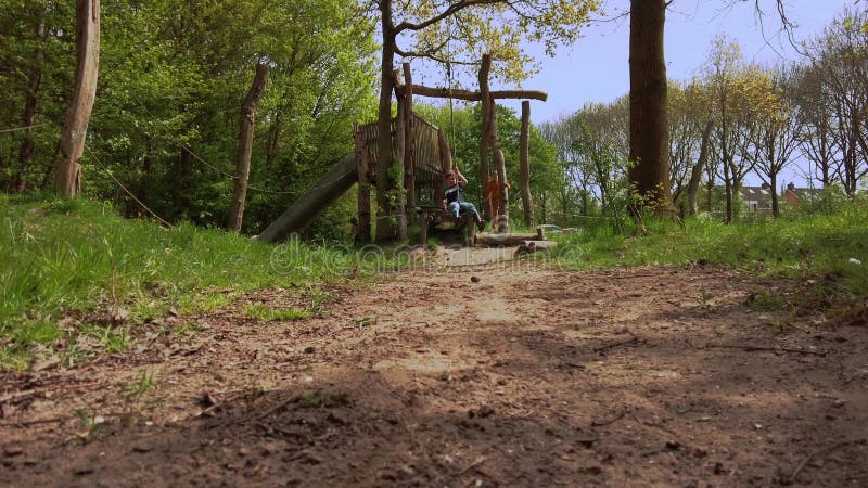 Tre glada barn leker i naturen och spelar upp zipline arkivfilmer