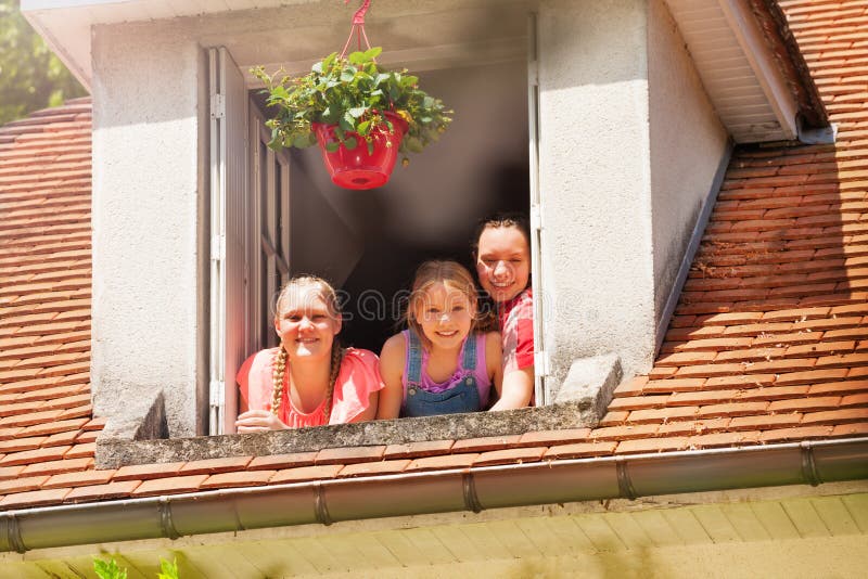 Tre le flickor i det öppna loftfönstret arkivfoto Tre le flickor i det öppna loftfönstret arkivfoto