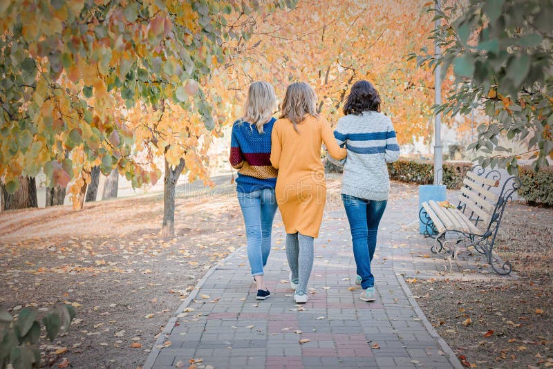 Tre migliori amici attraenti allegri delle giovani donne che camminano insieme e che si divertono esterno fotografia stock Tre migliori amici attraenti allegri delle giovani donne che camminano insieme e che si divertono esterno fotografia stock