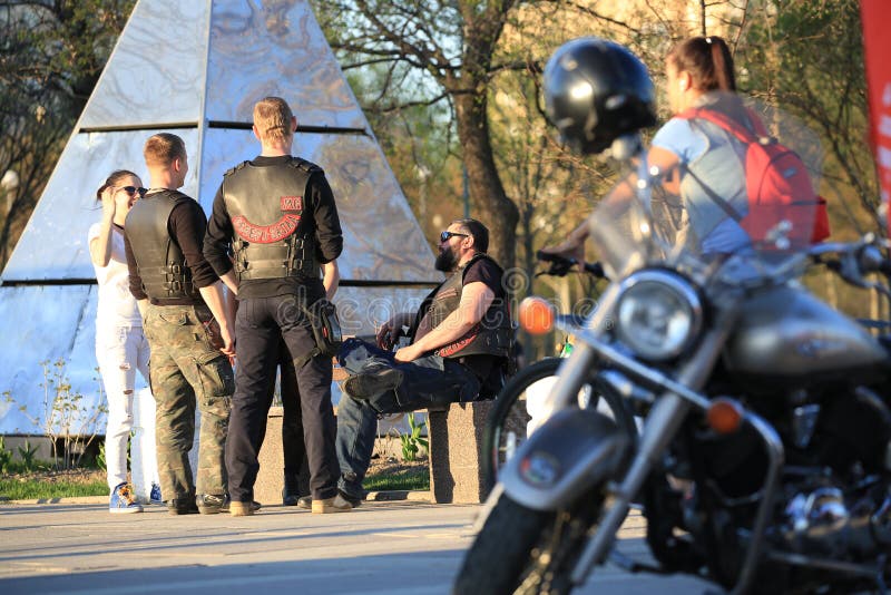 Tre motociclisti e una donna comunicare a vicenda su una sera soleggiata E fotografia stock libera da diritti Tre motociclisti e una donna comunicare a vicenda su una sera soleggiata E fotografia stock libera da diritti