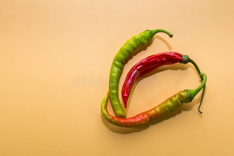 Tre peperoni caldi essiccati in diversi colori ripresi in fondo giallo fotografie stock Tre peperoni caldi essiccati in diversi colori ripresi in fondo giallo fotografie stock