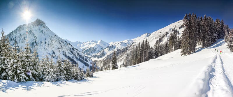 Tre personer som fotvandrar i berg, övervintrar landskap med djup snö på klar solig dag Allgau Bayern, Tyskland arkivfoto
