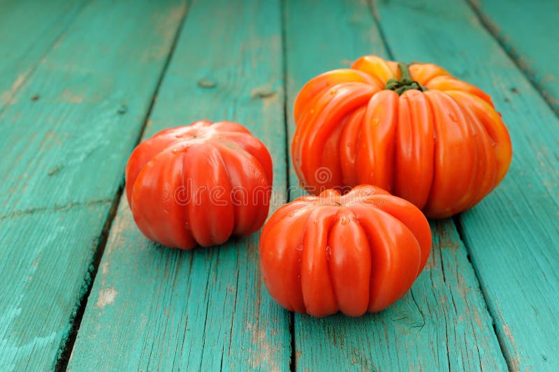 Tre pomodori organici freschi di cimelio su turchese di legno misero fotografia stock libera da diritti Tre pomodori organici freschi di cimelio su turchese di legno misero fotografia stock libera da diritti