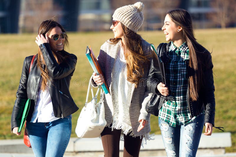 Tre ragazze degli studenti che camminano nella città universitaria dell'università immagini stock Tre ragazze degli studenti che camminano nella città universitaria dell'università immagini stock