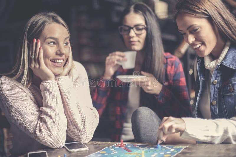 Tre ragazze felici che giocano gioco da tavolo immagini stock Tre ragazze felici che giocano gioco da tavolo immagini stock