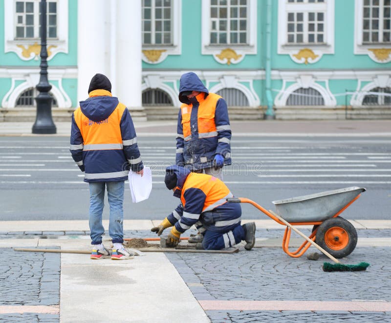 Three workers repair paving stones in the city square, Palace Square, St. Petersburg, Russia, April 22, 2024. Three workers repair paving stones in the city square, Palace Square, St. Petersburg, Russia, April 22, 2024