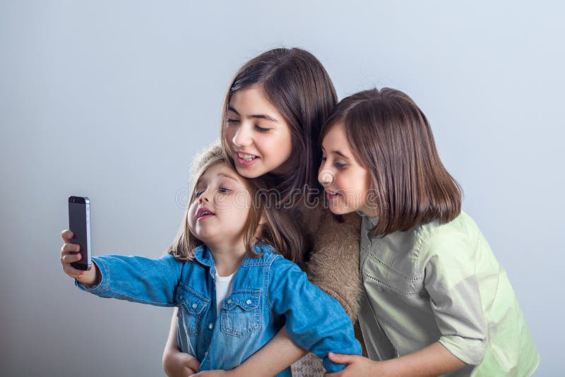 Tre sorelle che posano e che prendono i selfies nello studio fotografie stock libere da diritti