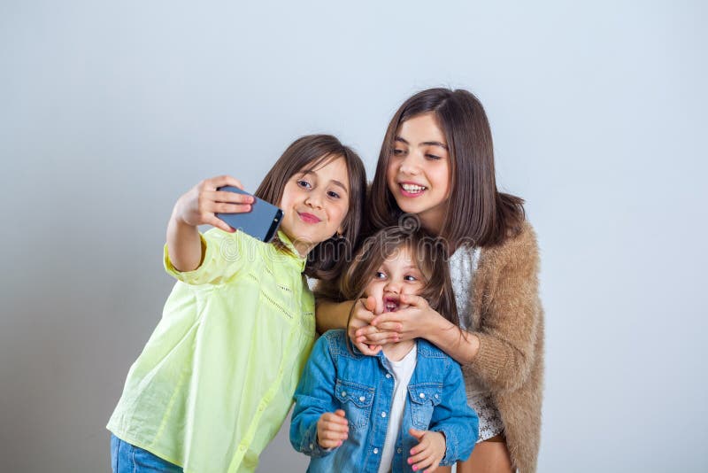 Tre sorelle che posano e che prendono i selfies nello studio immagine stock
