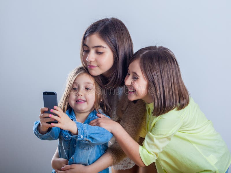 Tre sorelle che posano e che prendono i selfies nello studio immagine stock libera da diritti