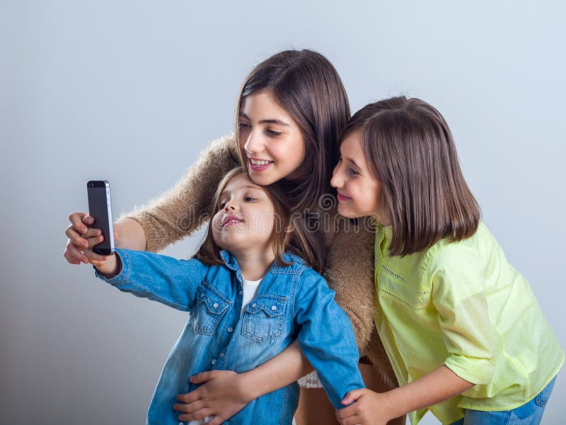 Tre sorelle che posano e che prendono i selfies nello studio fotografie stock libere da diritti