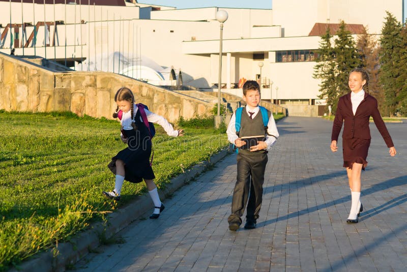 Tre studenti camminano nel parco con le cartelle dopo le classi fotografia stock libera da diritti Tre studenti camminano nel parco con le cartelle dopo le classi fotografia stock libera da diritti