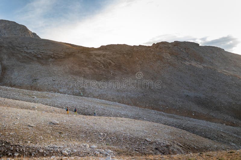 Tre turisti con zaini in montagna. i turisti attraversano le montagne rocciose. riposo attivo durante l'escursionismo in montagna. fotografia stock libera da diritti