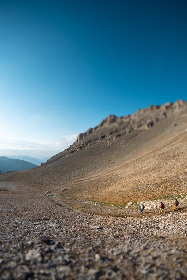 Tre turisti con zaini in montagna. i turisti attraversano le montagne rocciose. riposo attivo durante l'escursionismo in montagna. fotografia stock