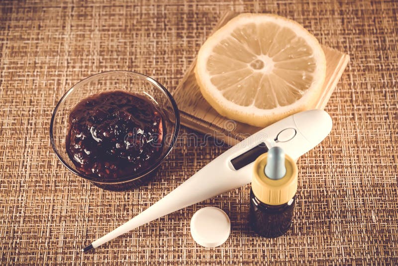 Treatment of colds and flu. Various medications, thermometer, cold pills, throat spray, nasal drops, lemon on a brown background.