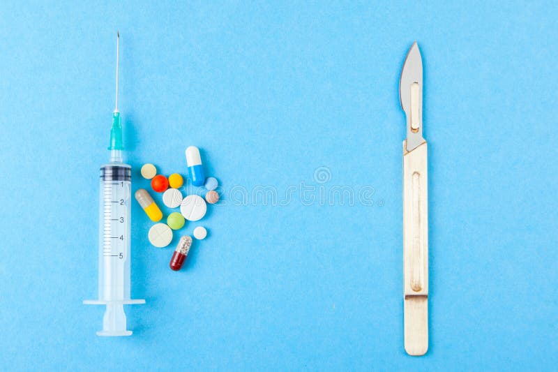 Treatment with drugs and pills or doing surgery. Syringe with pills and scalpel on blue background