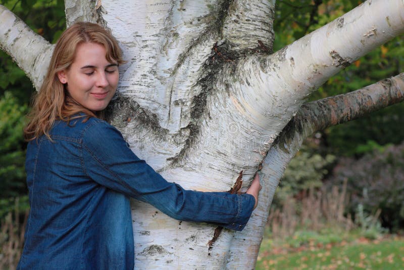 Woman hugging birch tree by closed eyes and smile