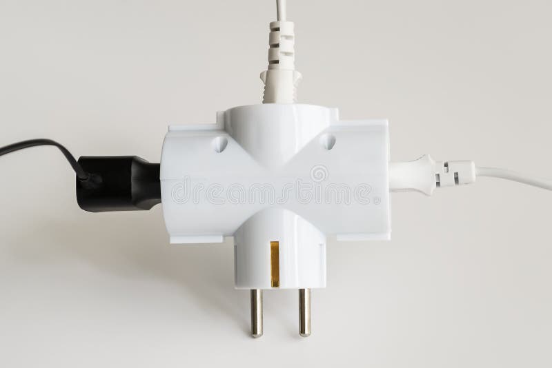 Tree plugs socketed into white electric splitter on a white background. Splitter for simultaneous switching of three electrical royalty free stock photo