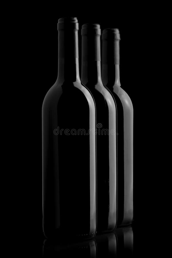 Trei sticle elegante de vin pe fond negru royalty free stock photos
