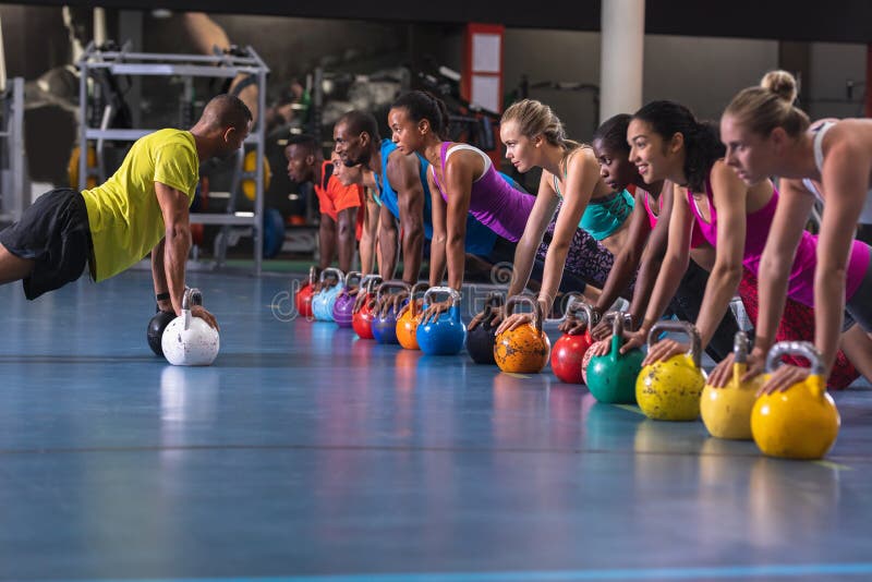 Treinador masculino treinando mulheres para se exercitar com kettlebell foto de stock royalty free Treinador masculino treinando mulheres para se exercitar com kettlebell foto de stock royalty free