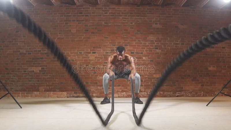 Treinamento africano muscular do homem com corda no treinamento funcional no gym Movimento lento