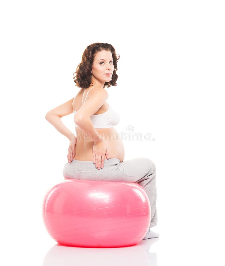 Treinamento moreno grávido da mulher dos jovens com uma bola da aptidão fotografia de stock Treinamento moreno grávido da mulher dos jovens com uma bola da aptidão fotografia de stock