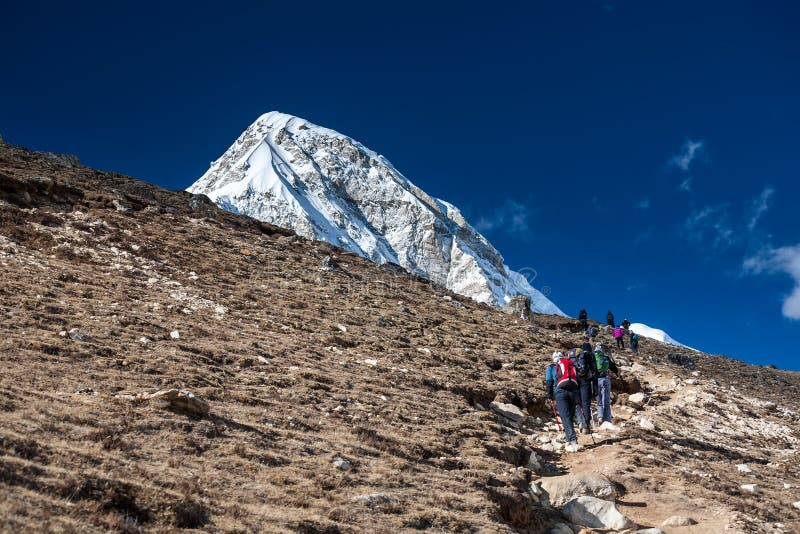 Trekker approchant la montagne de PumoRi en vallée de Khumbu sur un chemin à image stock Trekker approchant la montagne de PumoRi en vallée de Khumbu sur un chemin à image stock