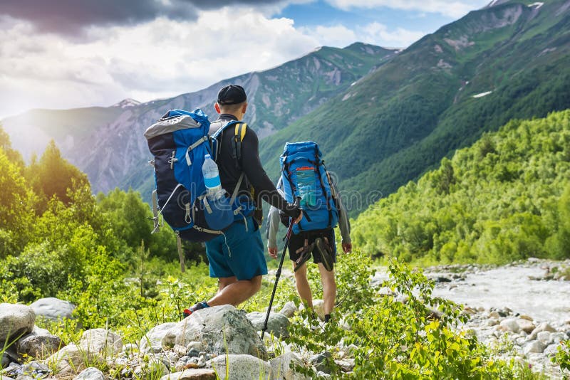 Trekking in mountains. Mountain hiking. Tourists with backpacks hike on rocky way near river. Wild nature with beautiful views. Sport tourism in Svaneti, Georgia. Hikers and climbers in mounts