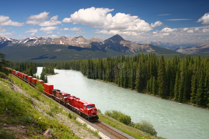 Tren de carga que se mueve a lo largo del río del arqueamiento en R canadiense fotografía de archivo libre de regalías Tren de carga que se mueve a lo largo del río del arqueamiento en R canadiense fotografía de archivo libre de regalías