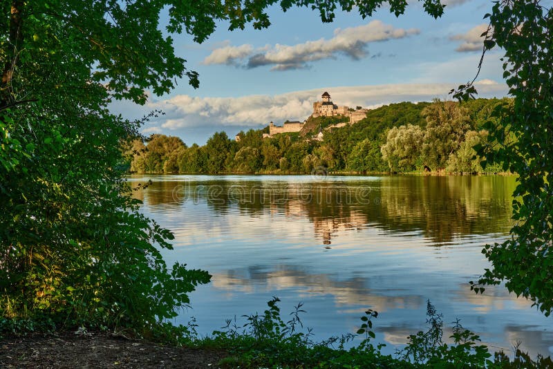 Hrad nad riekou. Pohľad na pravý breh. Orámované listami stromov. Trenčín, Slovensko.