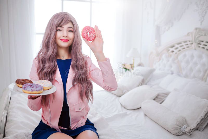 Trendig missfoster Glamour som ler den härliga kvinnan med långt lila hår, rymmer färgrika donuts i händer efter royaltyfria bilder Trendig missfoster Glamour som ler den härliga kvinnan med långt lila hår, rymmer färgrika donuts i händer efter royaltyfria bilder
