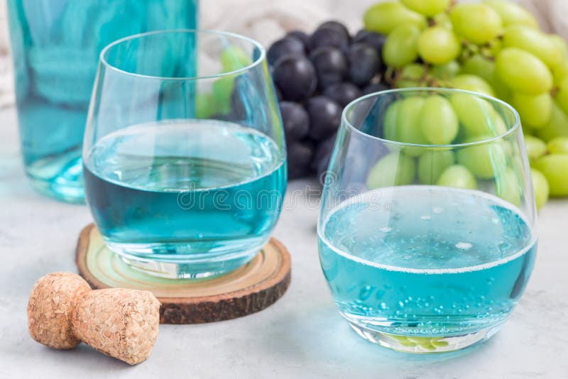 Trendy blue moscato wine in glass and in bottle, green and red grape on background, horizontal