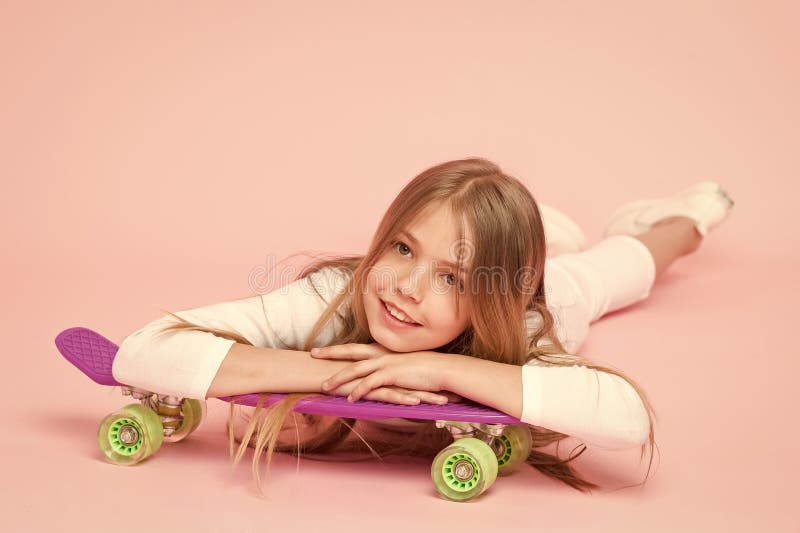 Trendy Girl Alla ragazza piace andare in skateboard Stile di vita attivo Ragazza che si diverte con uno sfondo rosa sulla tavola