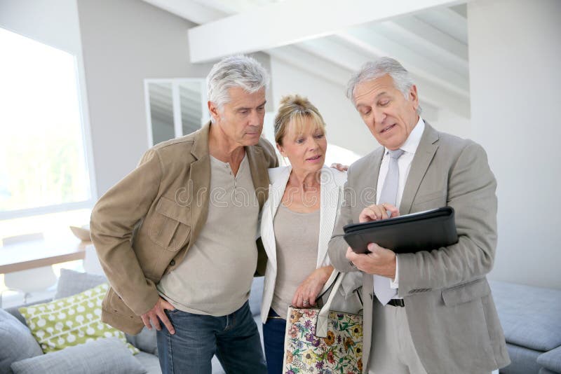 Trendy senior couple with real-estate agent visiting new house