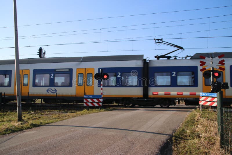 Treno bianco giallo blu dello sprinter ad un incrocio di ferrovia in Moordrecht fotografie stock