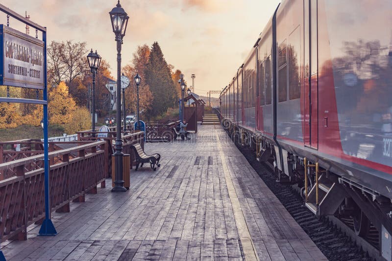 Treno passeggeri in piedi accanto alla piattaforma di legno al tramonto prima della partenza immagine stock libera da diritti