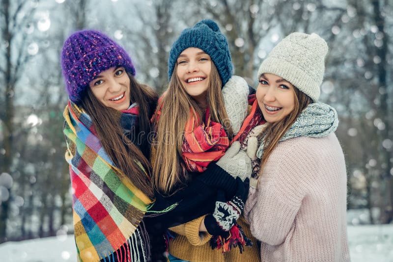 Tres amigas afuera con sombreros de punto divirtiéndose en un clima frío de nieve Grupo de jóvenes amigas al aire libre foto de archivo Tres amigas afuera con sombreros de punto divirtiéndose en un clima frío de nieve Grupo de jóvenes amigas al aire libre foto de archivo