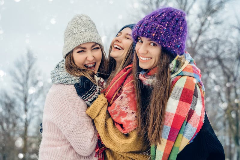 Tres amigas afuera con sombreros de punto divirtiéndose en un clima frío de nieve Grupo de jóvenes amigas al aire libre foto de archivo Tres amigas afuera con sombreros de punto divirtiéndose en un clima frío de nieve Grupo de jóvenes amigas al aire libre foto de archivo