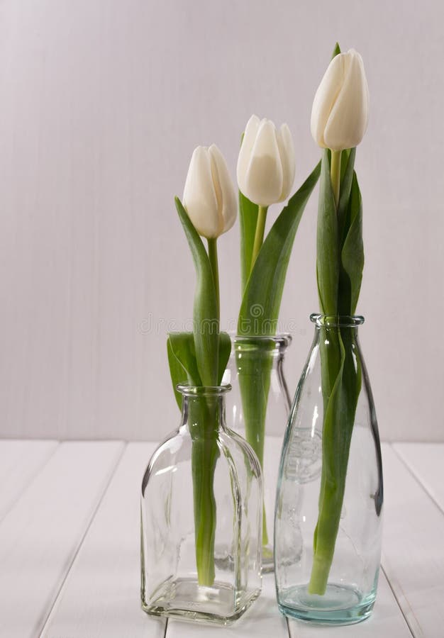 Tres botellas de cristal con los tulipanes fotografía de archivo Tres botellas de cristal con los tulipanes fotografía de archivo