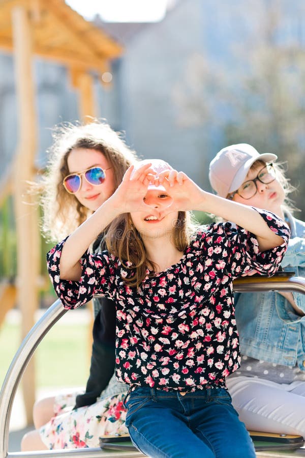 Tres chicas jóvenes en el patio que se sienta en el pequeño carrusel - oiga fotos de archivo libres de regalías Tres chicas jóvenes en el patio que se sienta en el pequeño carrusel - oiga fotos de archivo libres de regalías