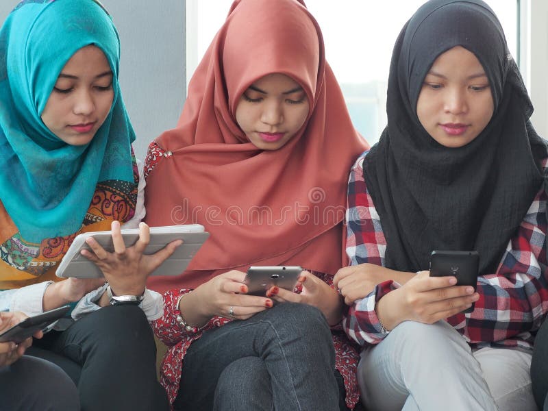 Tres chicas jóvenes que llevan el hijab usando los dispositivos móviles fotografía de archivo libre de regalías Tres chicas jóvenes que llevan el hijab usando los dispositivos móviles fotografía de archivo libre de regalías