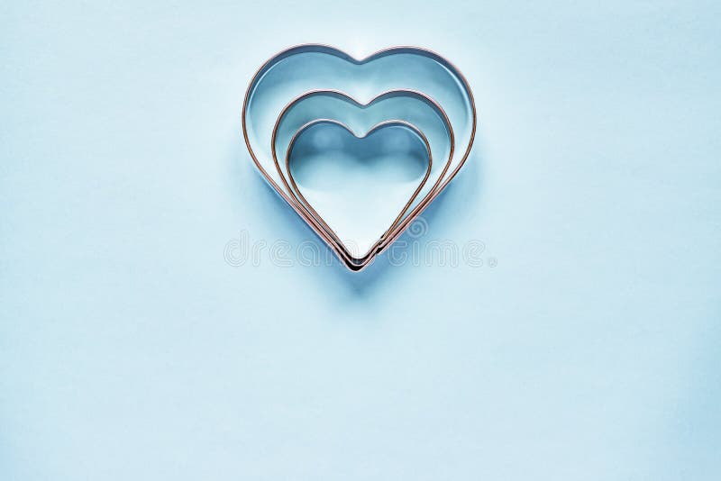 Tres cortadores de la galleta del metal en forma del corazón en fondo azul claro con el espacio de la copia imagen de archivo libre de regalías Tres cortadores de la galleta del metal en forma del corazón en fondo azul claro con el espacio de la copia imagen de archivo libre de regalías