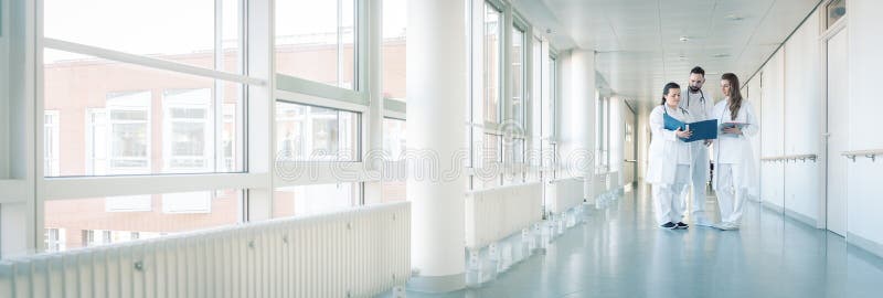 Tres doctores en el pasillo del hospital que tiene reunión corta foto de archivo libre de regalías Tres doctores en el pasillo del hospital que tiene reunión corta foto de archivo libre de regalías