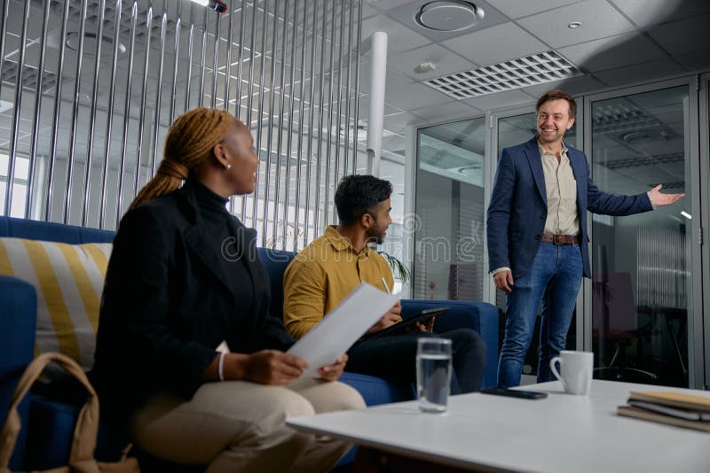 Three multiracial young adults wearing businesswear smiling with documents and technology in office. Three multiracial young adults wearing businesswear smiling with documents and technology in office