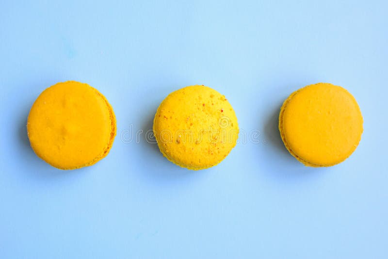Tres macarons amarillos brillantes sobre fondo azul claro, vista superior foto de archivo libre de regalías Tres macarons amarillos brillantes sobre fondo azul claro, vista superior foto de archivo libre de regalías