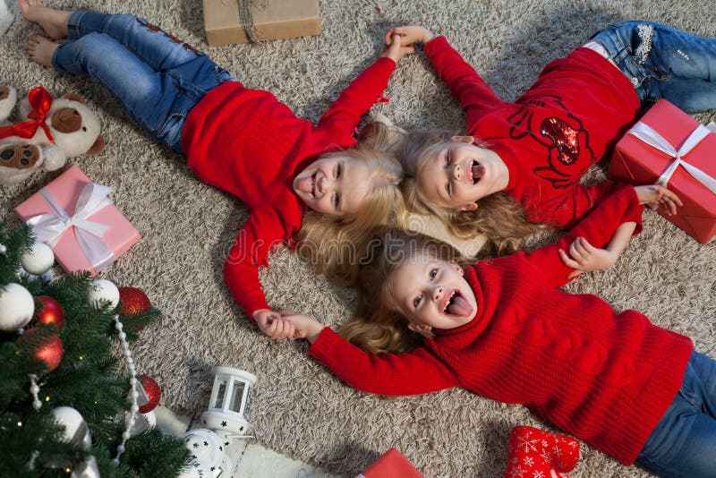 Tres muchachas abren luces de la guirnalda del árbol de navidad del Año Nuevo de los regalos de Navidad fotos de archivo libres de regalías Tres muchachas abren luces de la guirnalda del árbol de navidad del Año Nuevo de los regalos de Navidad fotos de archivo libres de regalías