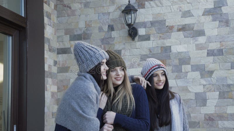 Tres muchachas bonitas en los casquillos y la bufanda que presentan en la yarda metrajes