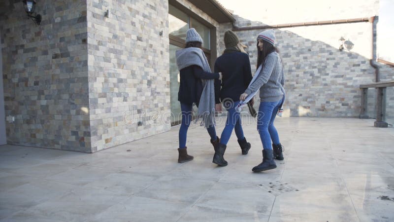 Tres muchachas bonitas en los casquillos y los suéteres que se divierten en la yarda almacen de metraje de vídeo