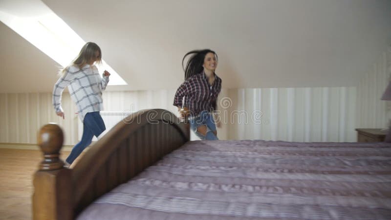 Tres muchachas bonitas que corren en las escaleras y que saltan en la cama para se relajan metrajes