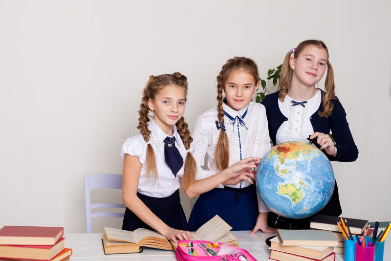 Tres muchachas de las colegialas aprenden la lección de la geografía del mundo en el mapa fotos de archivo Tres muchachas de las colegialas aprenden la lección de la geografía del mundo en el mapa fotos de archivo